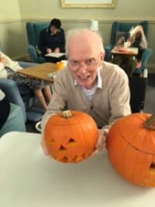 gentleman resident proudly showing his carved pumpkin