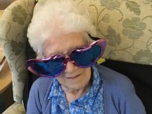 lady resident wearing big heart glasses at Valentine's music therapy