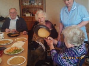 Lady resident tossing pancakes - Pancake Day 2017 2