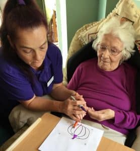 staff helping a resident with acetate Halloween colouring 
