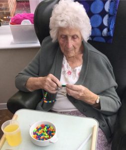 lady resident threading beads making candy canes