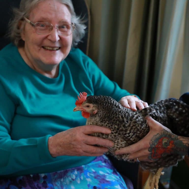 Resident smiling and socialising a chicken
