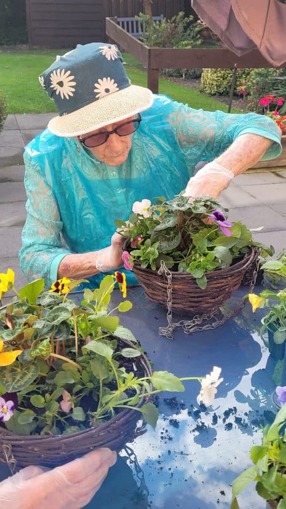 lady with floral bucket hat assembling hanging basket