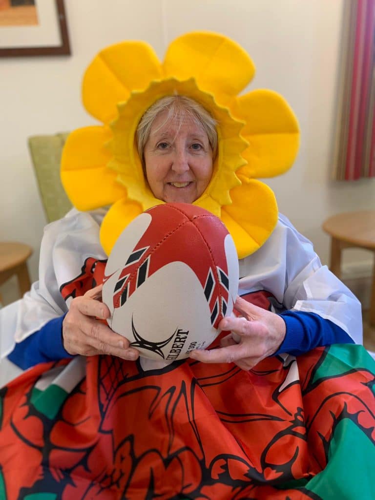 St David's Day - lady resident with daffodil hat and rugby ball