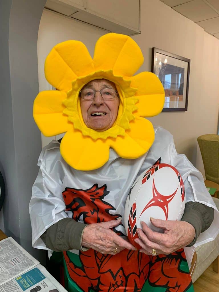 gentleman resident with glasses daffodil hat and rugby ball