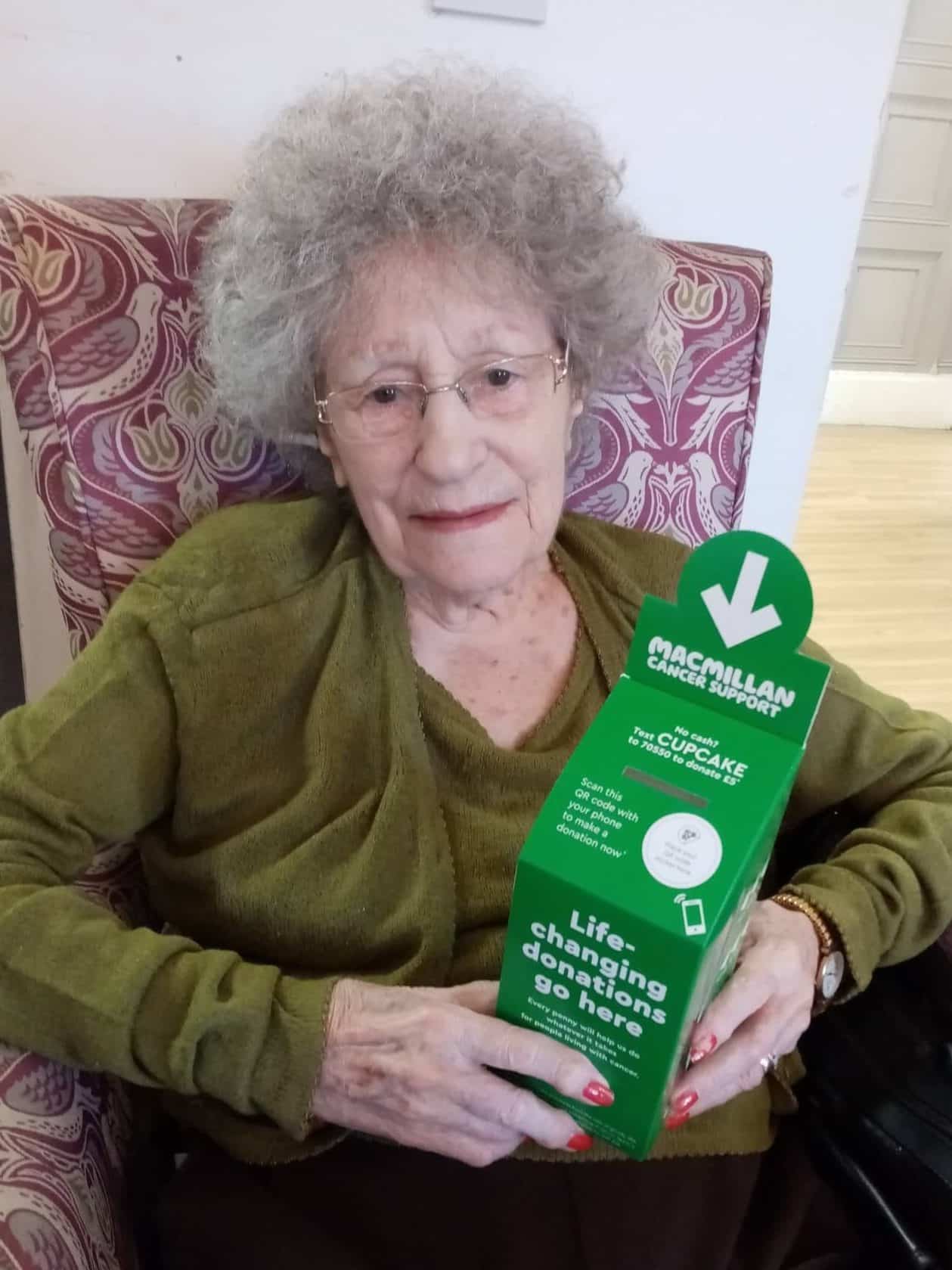 fun and fundraising - lady resident holding donation box for Macmillan